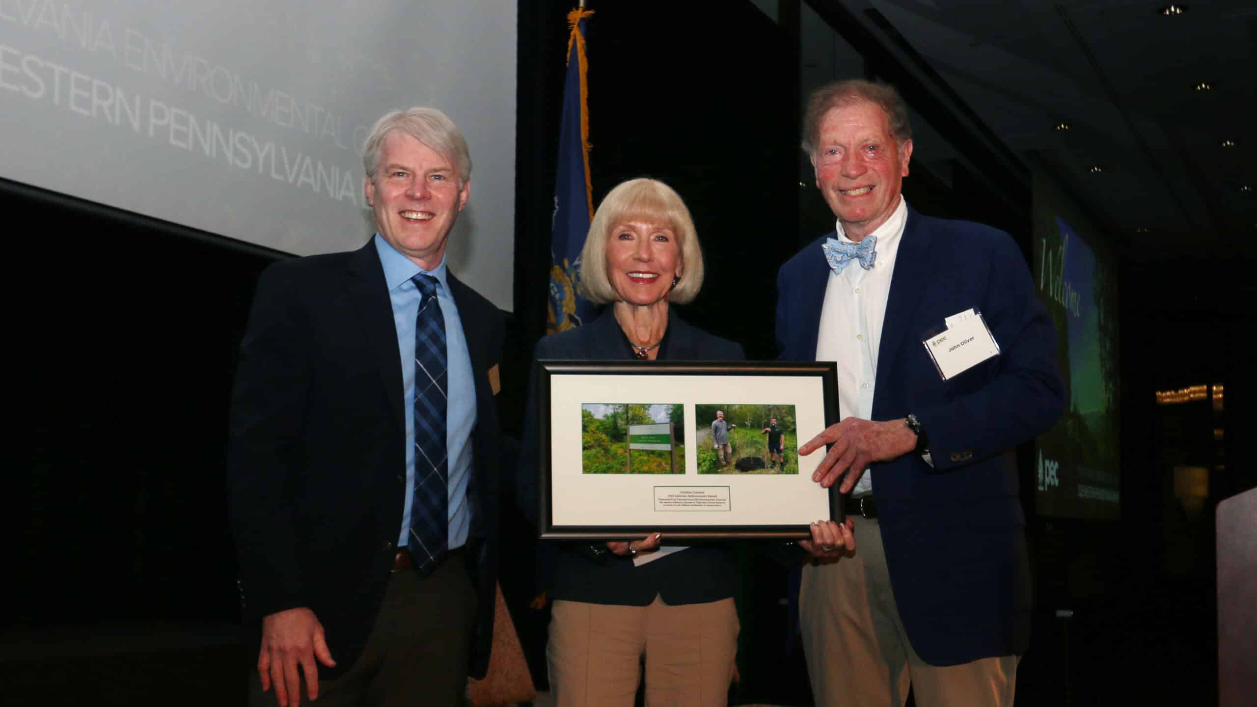 Cynthia Carrow, standing with PEC President Tom Gilbert, left, and former DEP Secretary John C. Oliver, right, received the Lifetime Achievement Award at the 2025 Western Pennsylvania Dinner.