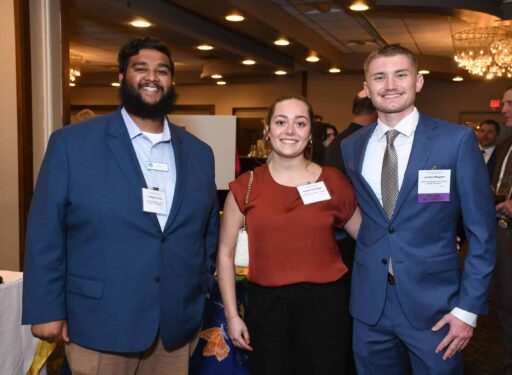 Two men and a woman standing together, posing for a picture. All three are formally dressed.