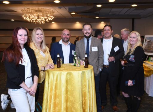 Group of formally dressed men and women standing around a table posing for a picture
